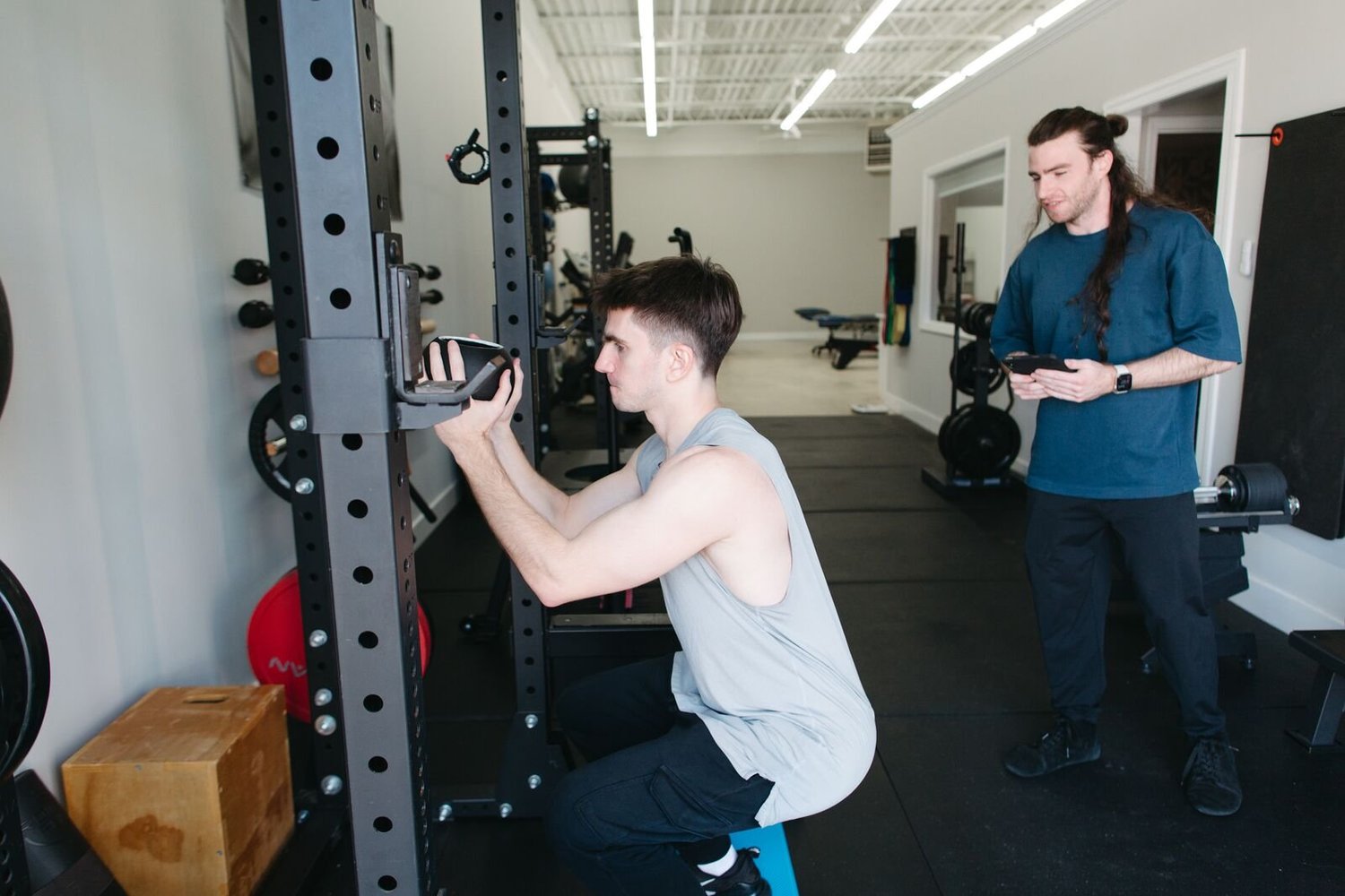 Griffin Connors coaches a client through a squat at CoGym's private personal training studio in Durham