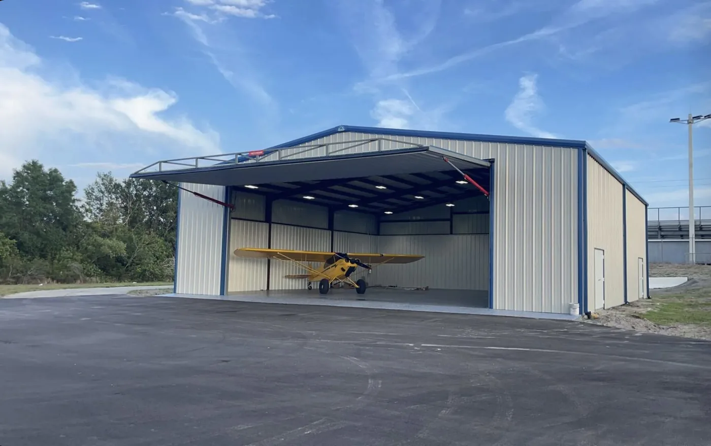 Steel aircraft hangar with a wide door and a light aircraft inside