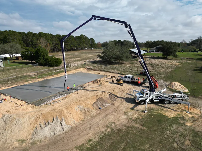 Concrete pump truck placing a building slab on a cleared pad