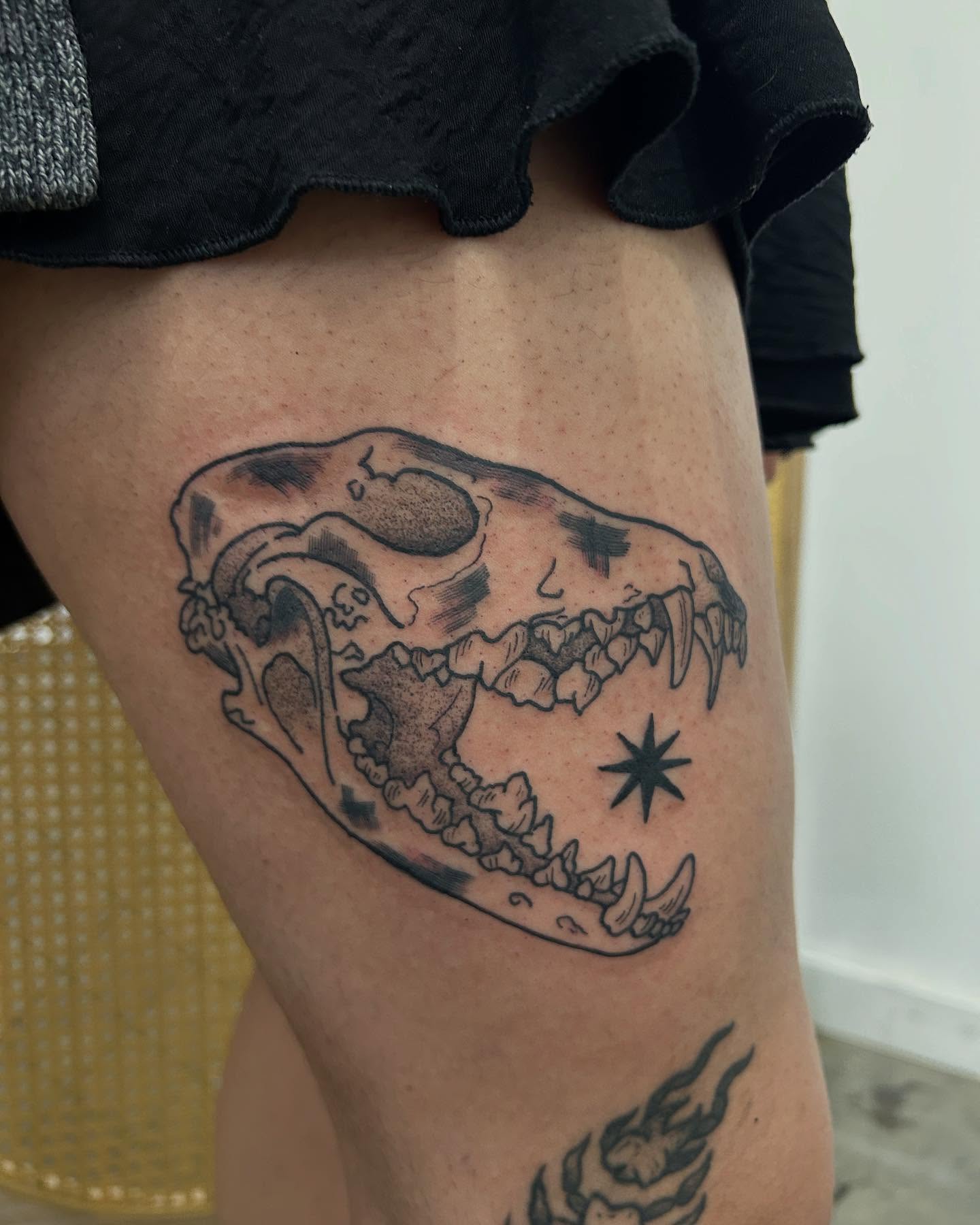An animal skull and a star tattooed on the thigh