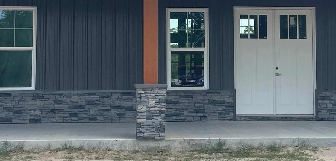 Dark steel entry wall with stone wainscot and a matching wrapped stone column